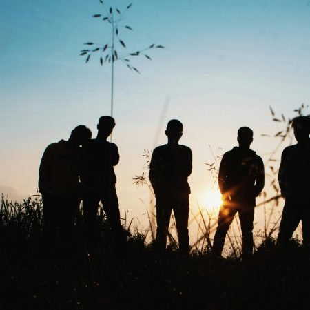 A group of friends silhouetted against the sunset, enjoying a moment in nature.