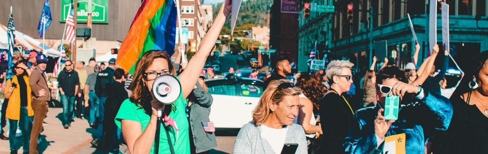 A vibrant protest with diverse participants holding flags and signs on a city street.